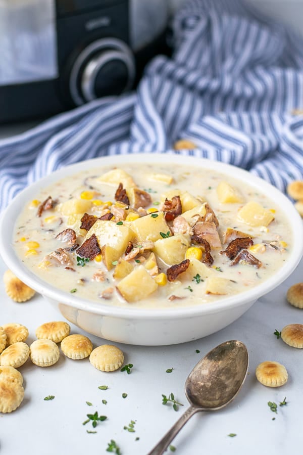 bowl full of clam chowder topped with bacon and thyme