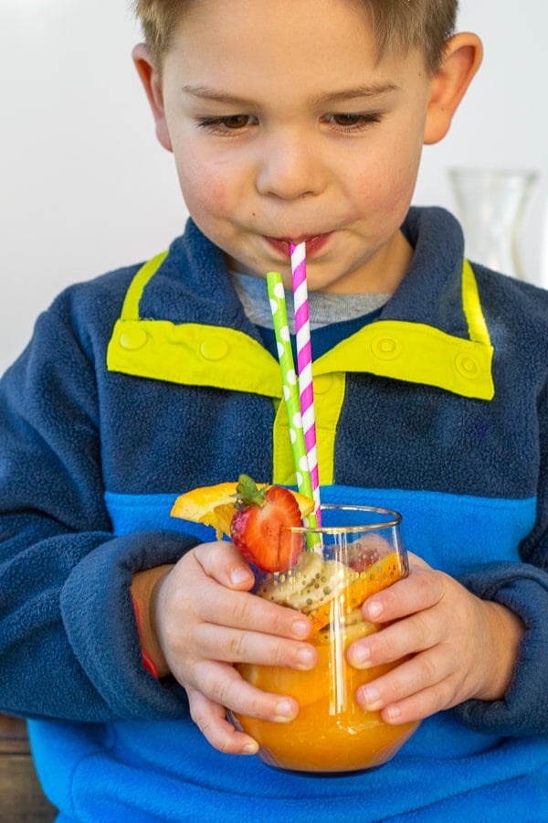 young boy sipping on an orange juice mocktail