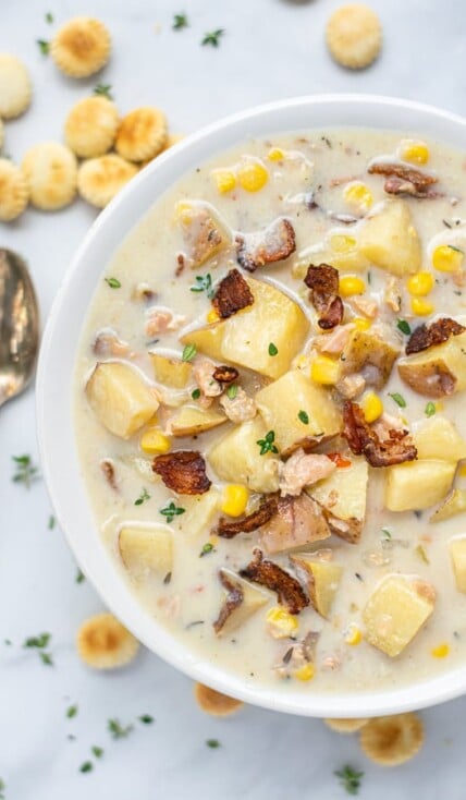 Healthy Clam Chowder in a white bowl with a spoon and oyster crackers