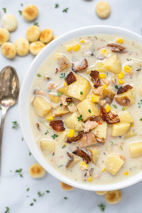 Healthy Clam Chowder in a white bowl with a spoon and oyster crackers