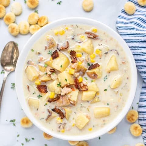 bowl full of clam chowder with a spoon and oyster crackers and a blue napkin