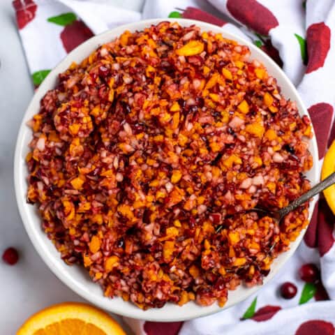 bowl of cranberry orange relish with a spoon on a table