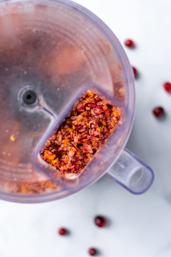 View of cranberry orange relish through the hole of the top of the food processor 