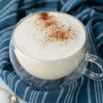 cinnamon honey milk steamer in a clear mug with cinnamon sprinkled on top