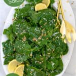 simple spinach salad with parmesan and walnuts on a large white platter