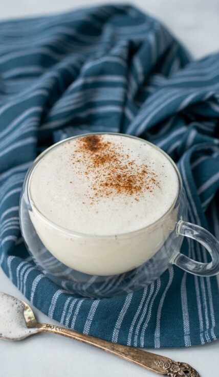 milk steamer drink in a clear mug with cinnamon sprinkled on top