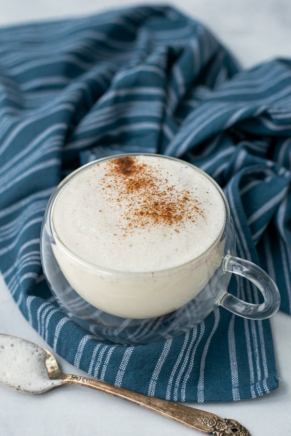 milk steamer drink in a clear mug with cinnamon sprinkled on top