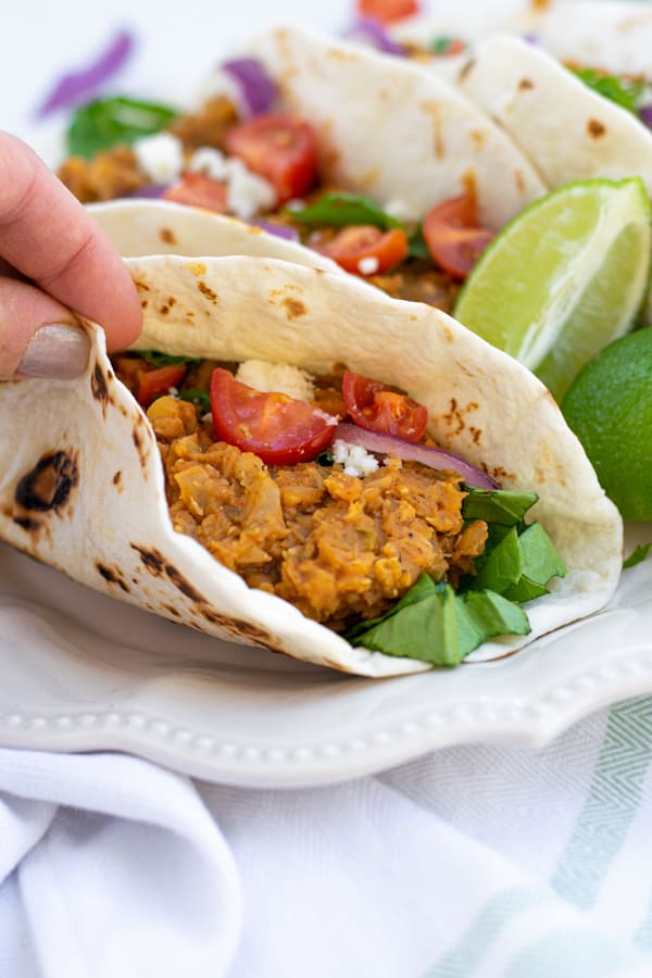 hand holding a red lentil taco in a flour tortilla