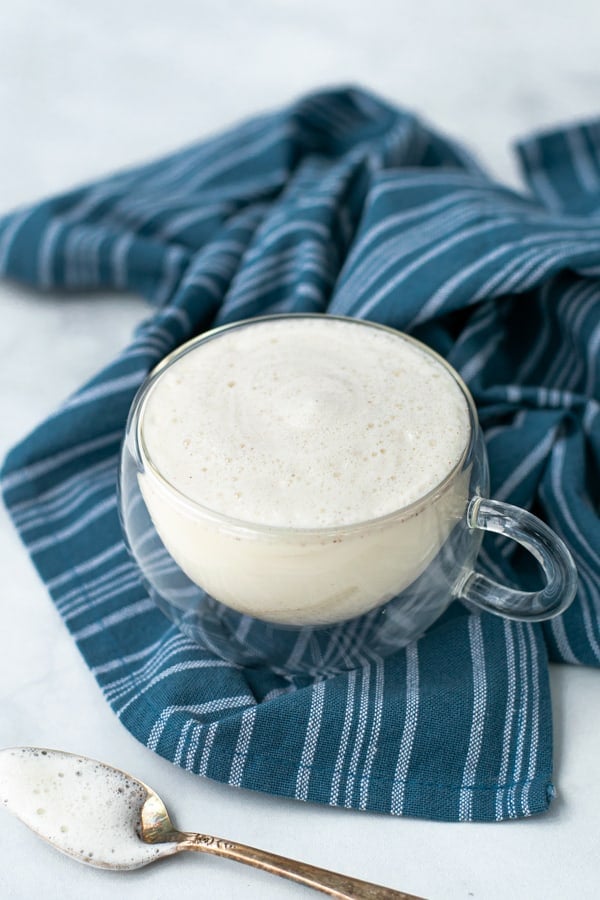 clear mug with cinnamon honey milk steamer and a blue towel