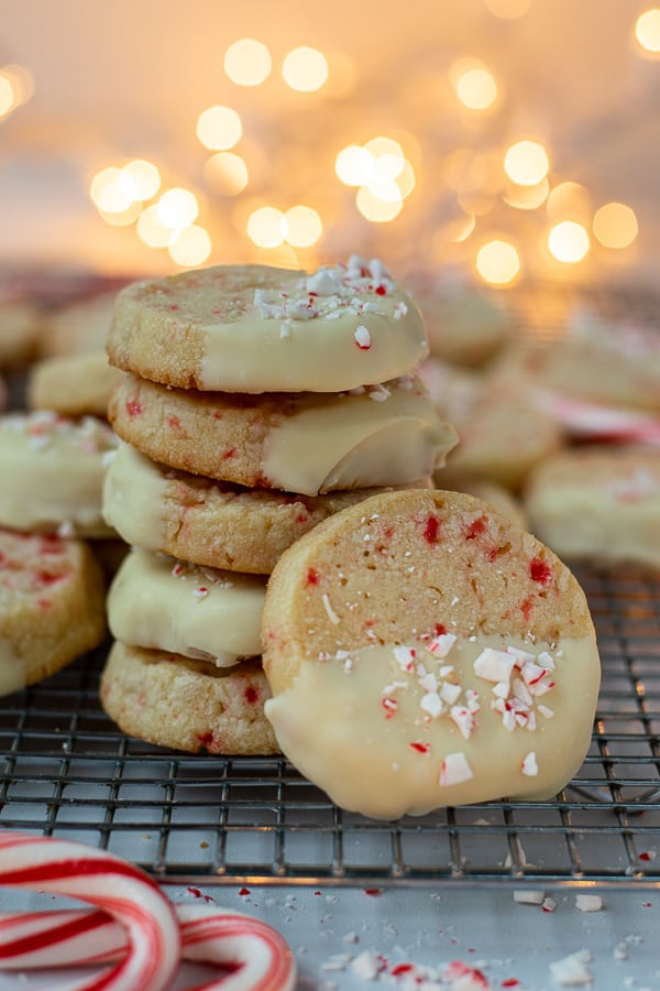 stack of white chocolate peppermint cookies on a cooling rack with christmas lights