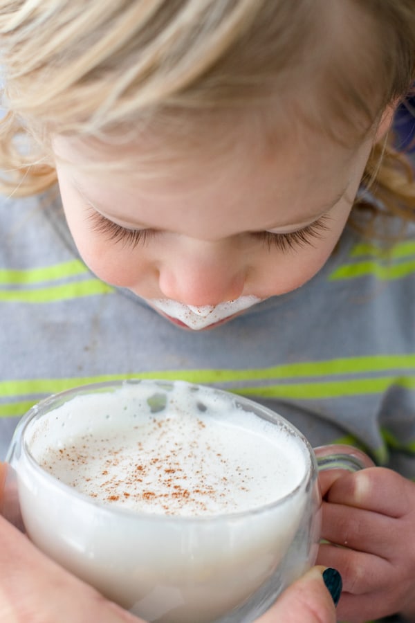 toddler going in for a sip of honey cinnamon milk steamer