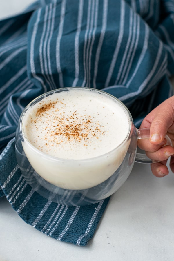 toddler hand grabbing a glass of steamed milk recipe