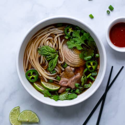 bowl of beef pho with bright green garnishes