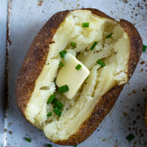 Close up of baked potato with butter and chives