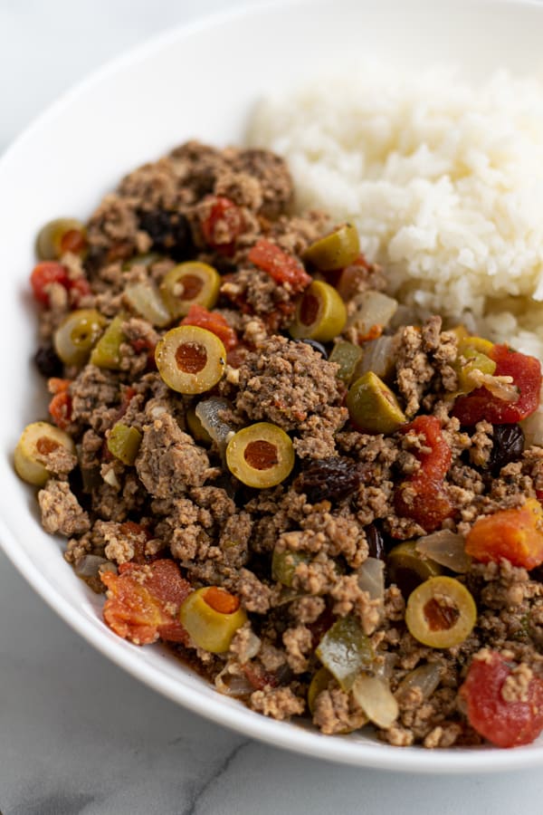 close up of cuban picadillo in a white bowl with rice