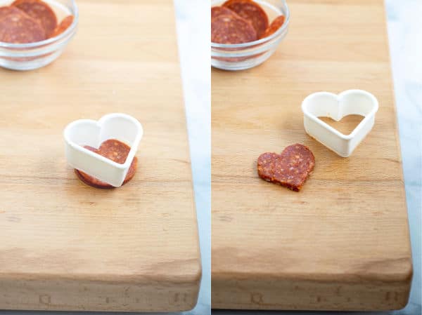 a small heart cookie cutter cutting pepperoni into a heart