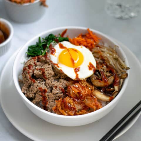 korean bibimbap bowl sitting on a table with chopsticks and kimchi