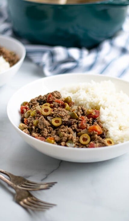 bowl of Cuban Picadillo with white rice on a table with forks