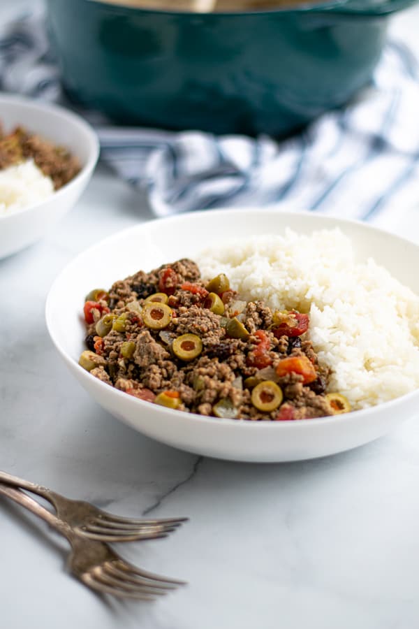 bowl of Cuban Picadillo with white rice on a table with forks