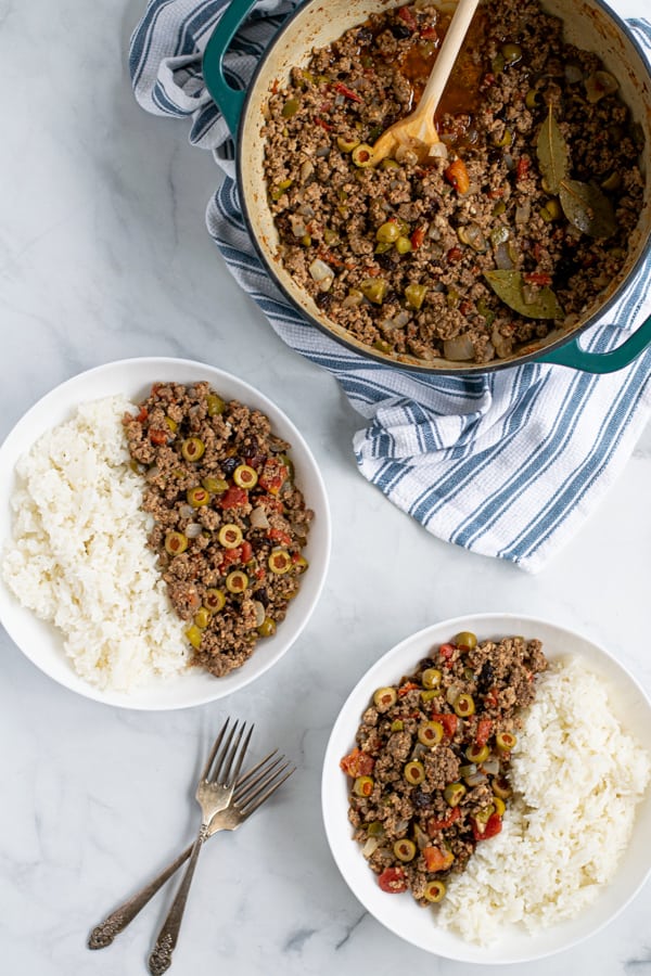 two bowls with rice and picadillo and a dutch oven filled with picadillo