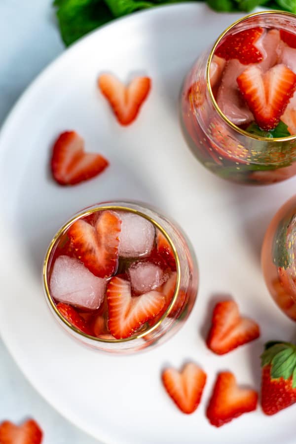flatly of glasses of rosé sangria on a plate with cut strawberry hearts