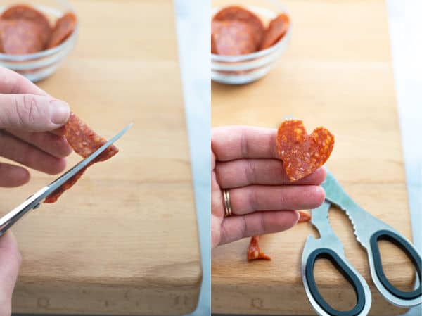 a kitchen scissors cutting a folded pepperoni into a heart shape