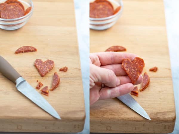 a paring knife cutting a stack of pepperoni into a heart