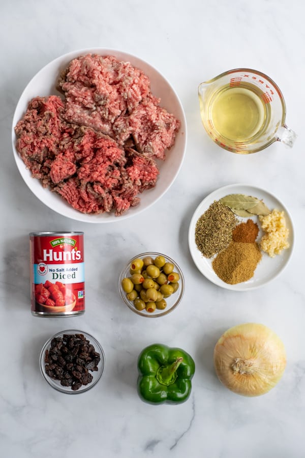 all of the ingredients needed to make picadillo laid out on a counter