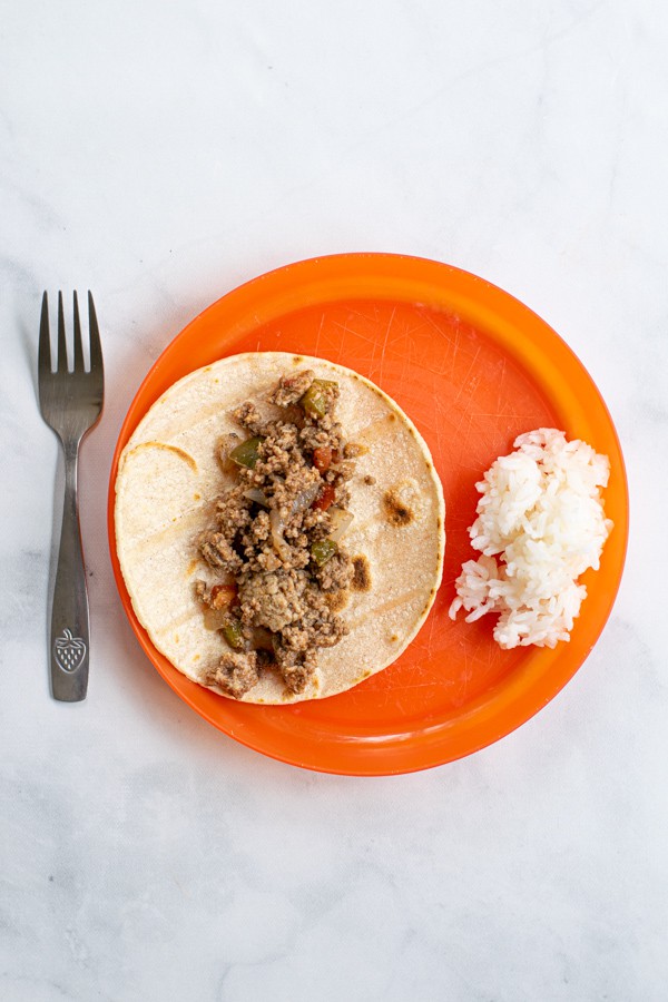 orange kids plate with a taco made from the meat of the picadillo as an option to serve this meal to kids