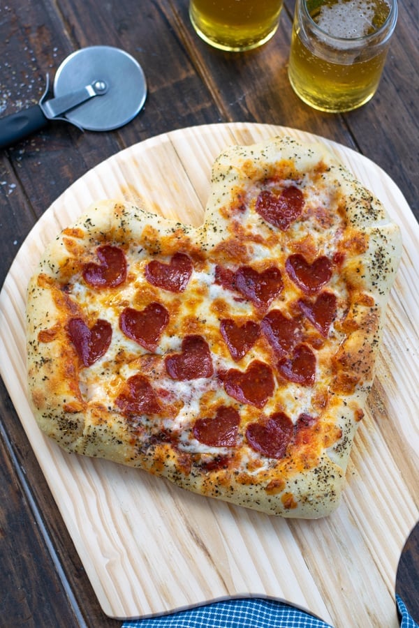 side angle of the heart shaped pizza freshly out of the oven with puffy crust and browned cheese