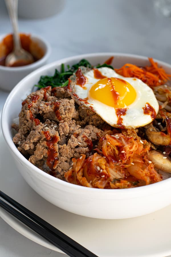 turkey bibimbap recipe in a bowl topped with an egg and drizzled with Gochujang sauce