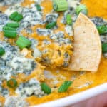 close up of tortilla chip being dipped into easy Buffalo Chickpea Dip
