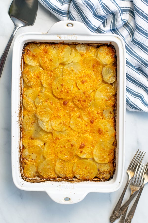 Au Gratin Potato Casserole dish sitting on a table with forks