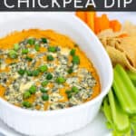 easy Buffalo Chickpea Dip in a small white baking dish with blue cheese and green onions with chips and vegetables for serving