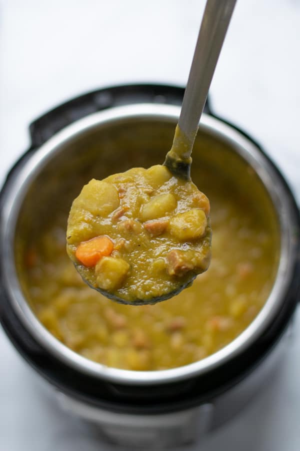 split pea soup in a ladle over top an electric pressure cooker