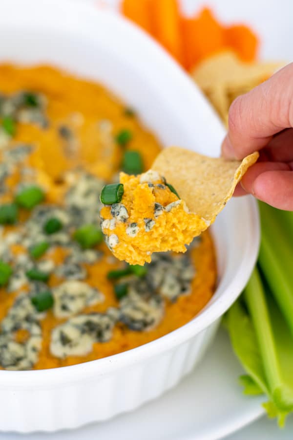 warm Buffalo Chickpea Dip scooped onto a chip