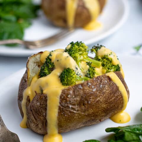 easy to make Broccoli Cheese Baked Potato on a plate with cheddar cheese sauce dripping down the side