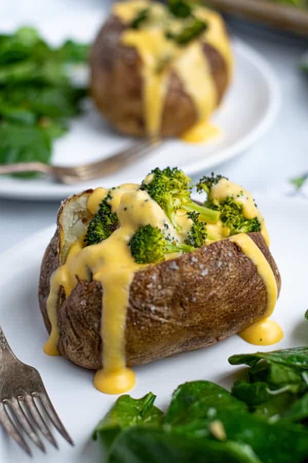 easy to make Broccoli Cheese Baked Potato on a plate with cheddar cheese sauce dripping down the side