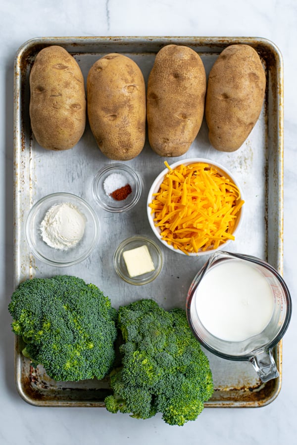 a sheet pan containing all of the ingredients needed to make broccoli cheese baked potatoes