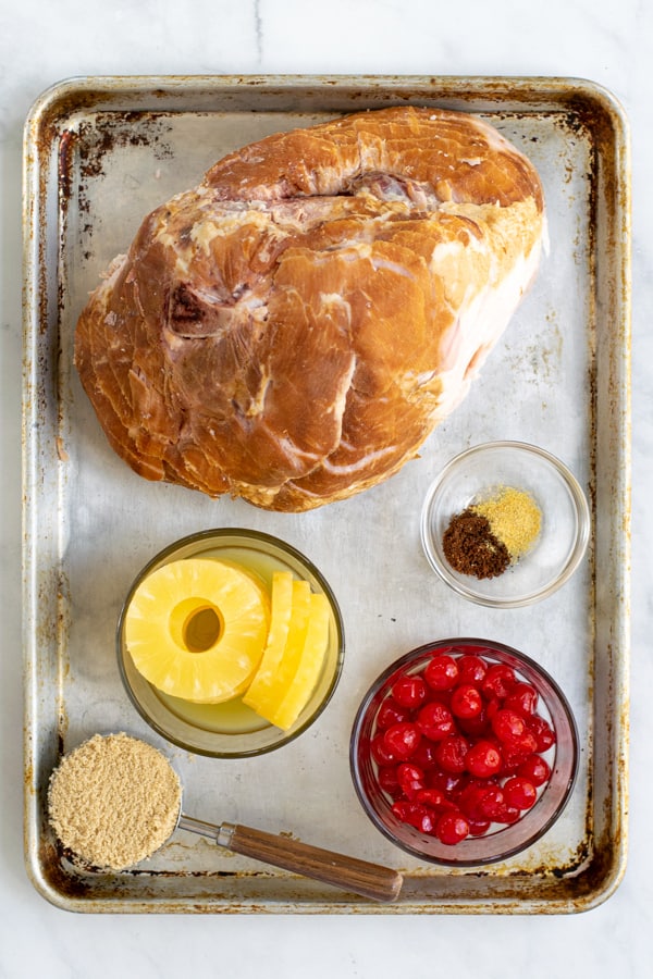 ingredients needed to make a ham in the crockpot sitting out on a sheet pan