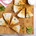 Pineterst Pin with post title showing two carnitas quesadillas on a wooden cutting board