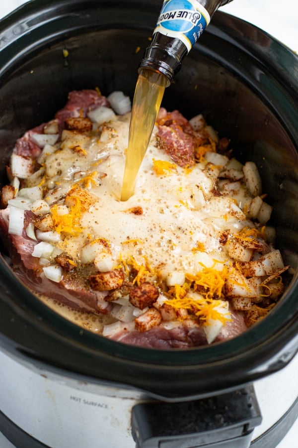 a blue moon beer being poured over the contents of the crockpot