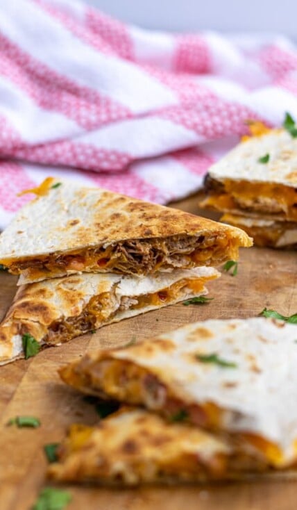 two pieces of carnitas quesadillas stacked on top of each other showing the pork and cheese on the inside