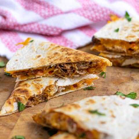 two pieces of carnitas quesadillas stacked on top of each other showing the pork and cheese on the inside