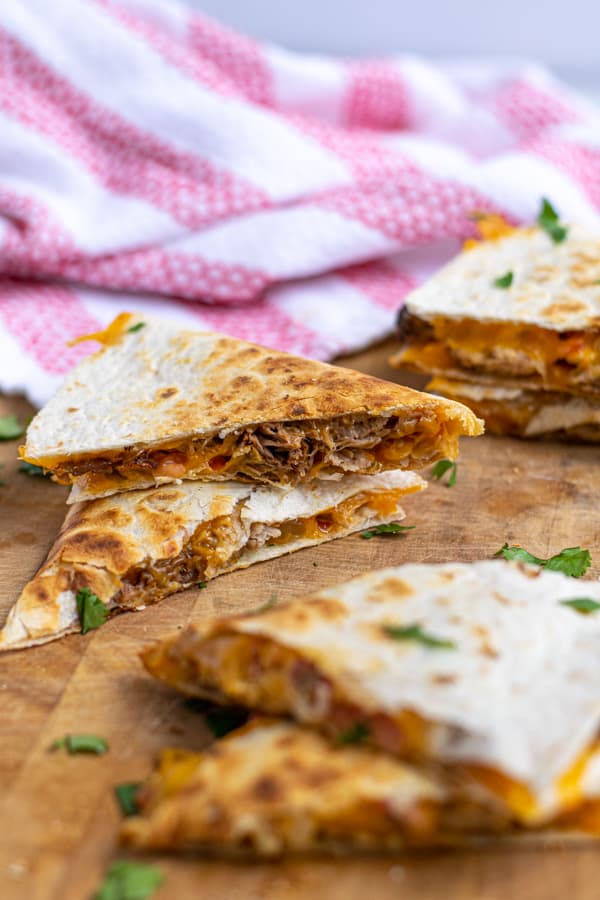 two pieces of carnitas quesadillas stacked on top of each other showing the pork and cheese on the inside