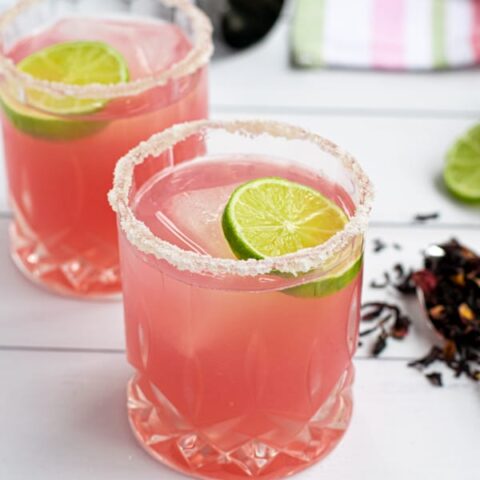 a glass of the best hibiscus margarita recipe with a salted-rim and a slice of lime