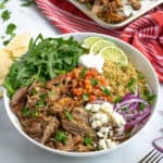 pinterest pin showing a large white bowl full of carnitas, quinoa, arugula, and fresh toppings!