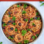 Spaghetti Puttanesca Pinterest Pin showing a large skillet full of pasta garnished with parsley