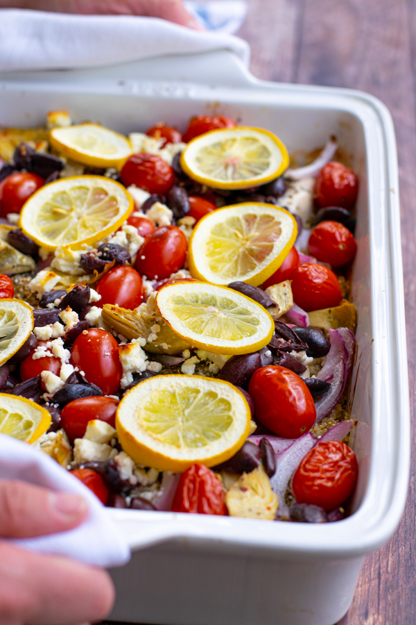 hand holding a baking dish with one pan greek chicken bake