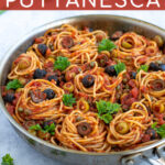 Pinterest Pin for Pasta Puttanesca shows a large skillet full of spaghetti